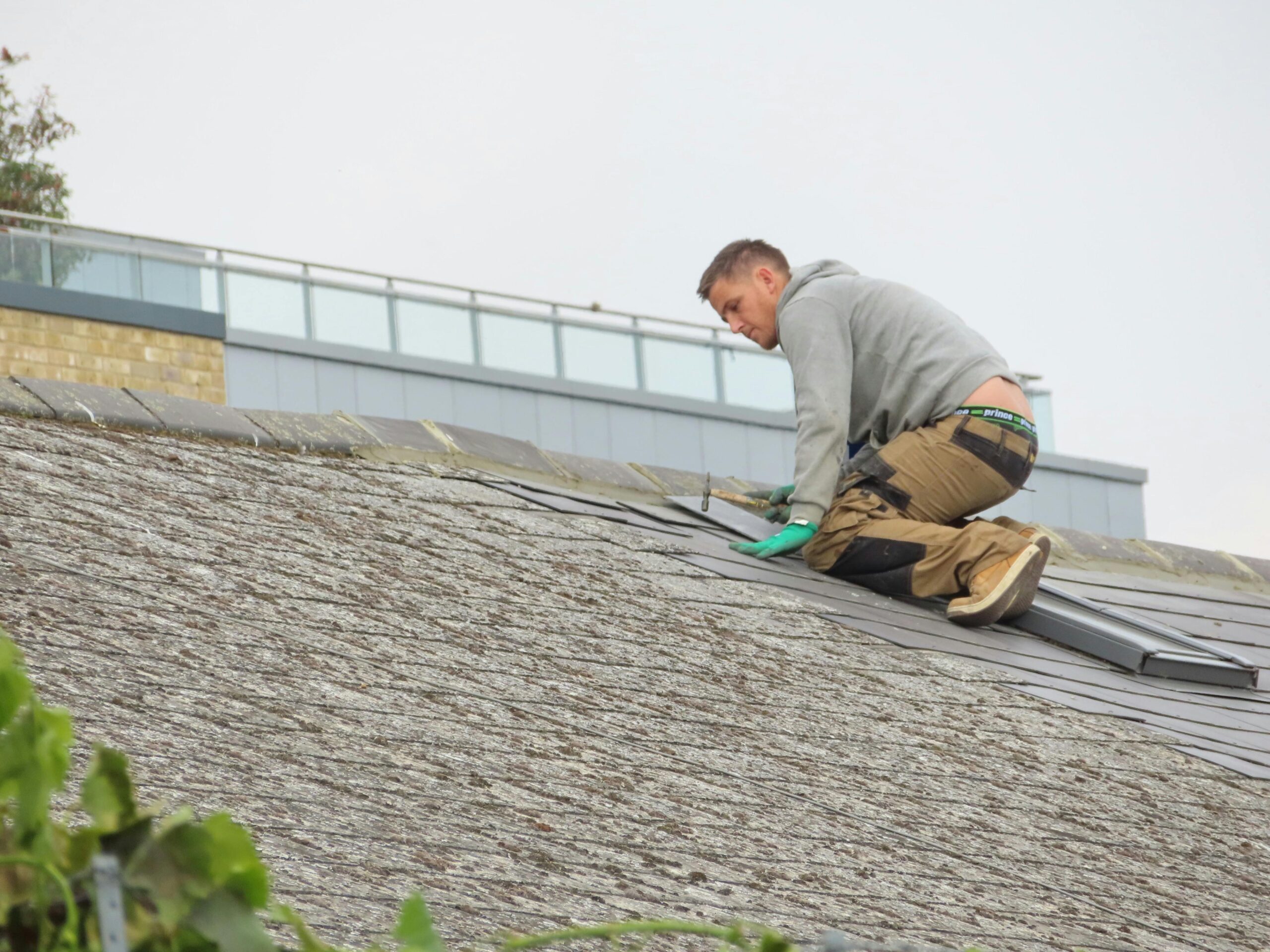 Professional roofer inspecting shingles for storm damage in Monroe County.